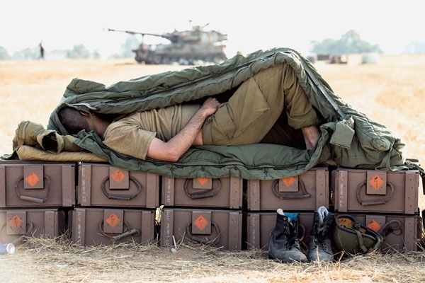 Izraeli katona lőszeres ládákon szundikál a Gázai övezetben. Az egész térség felrobbanhat