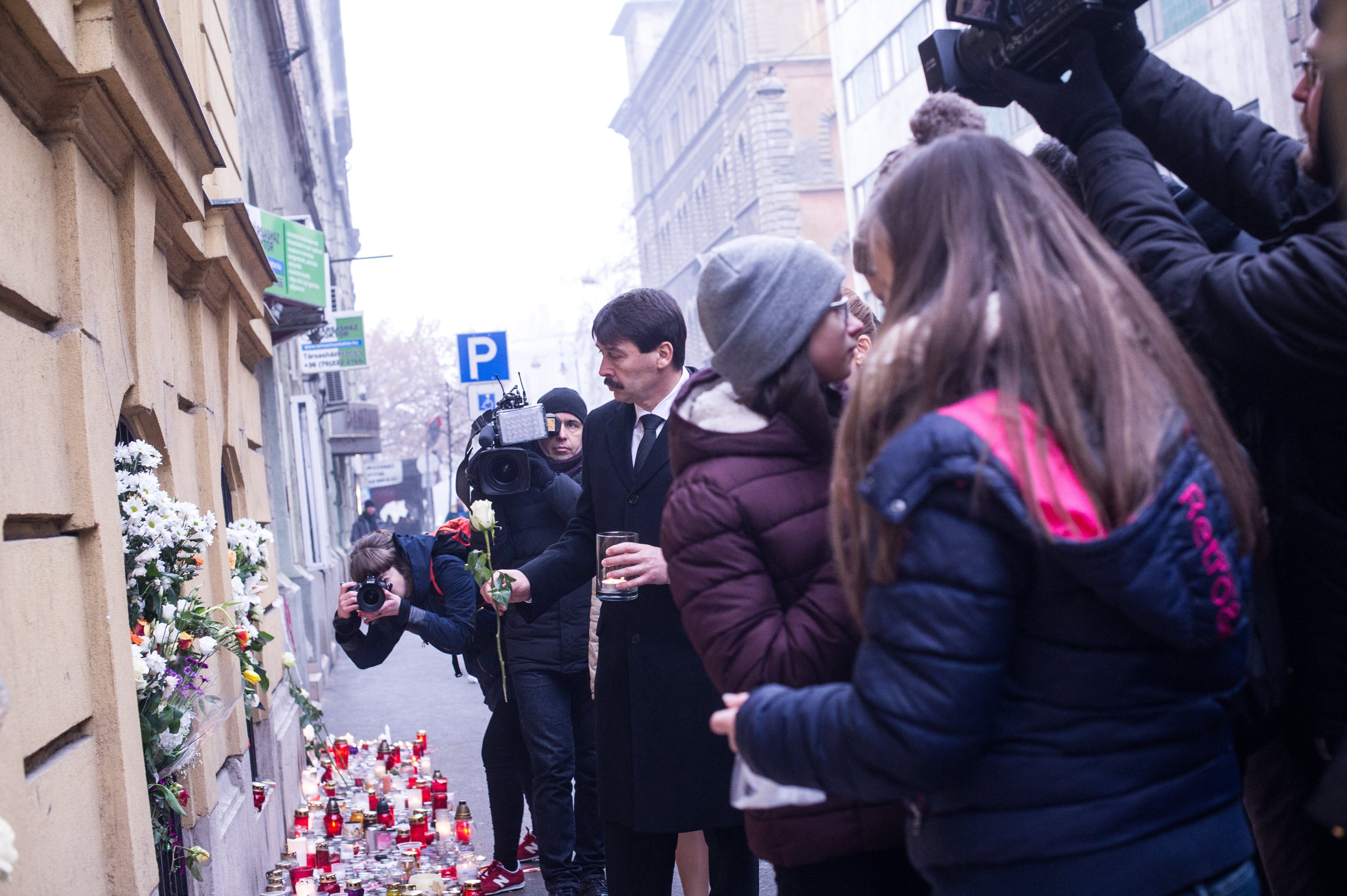 Áder János köztársasági elnök virággal és mécsessel a kezében a Szinyei Merse Pál Gimnázium épületénél.